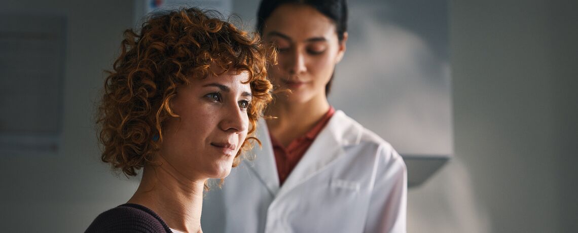 Un professionista con camice bianco consiglia una donna in Consulenza Plus nella sala di consulenza Sun Store sulla vaccinazione antitetanica.