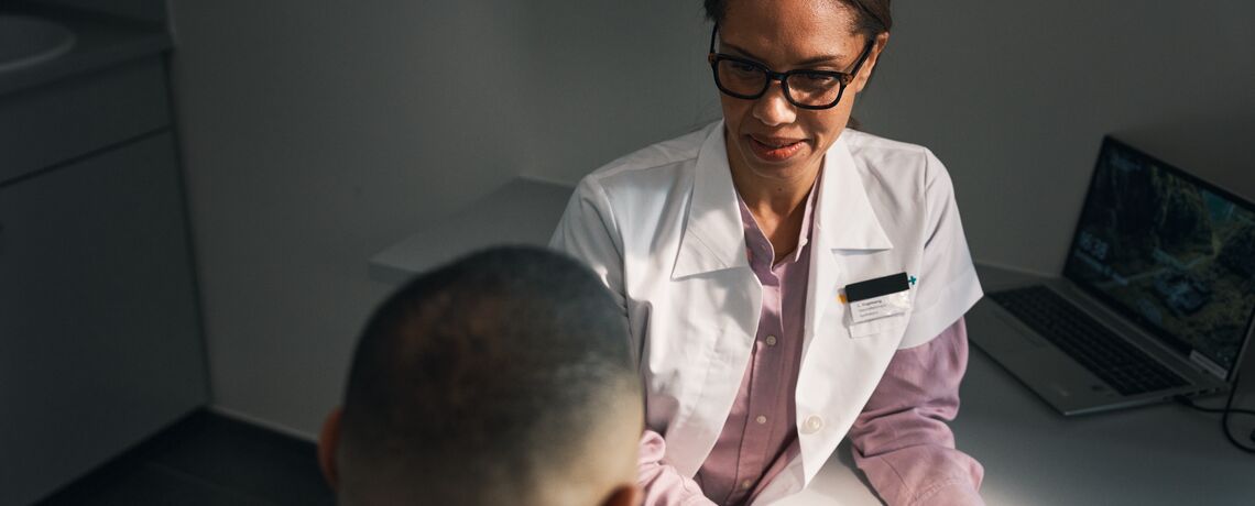 Un professionnel en blouse blanche conseille un homme en Consultation Plus dans une salle de consultation Sun Store sur les yeux rouges et irrités.